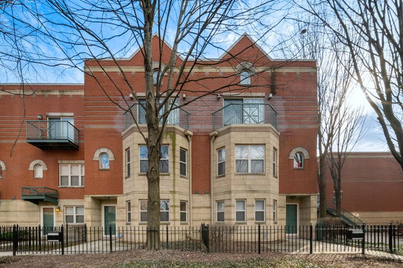 Front view of a multi-story brick building with balconies and a bay window.
