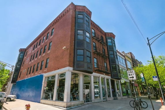 Front view of a multi-story brick building with large windows and fire escapes.