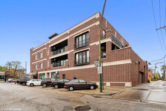 Front view of a multi-story brick building with balconies and large windows.