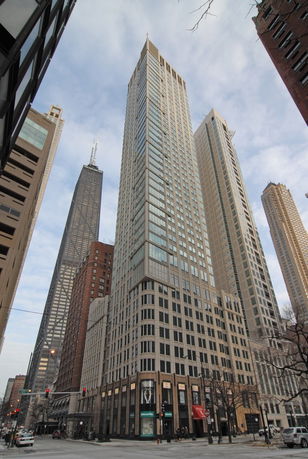 Front view of a modern high-rise building with glass and stone facade.