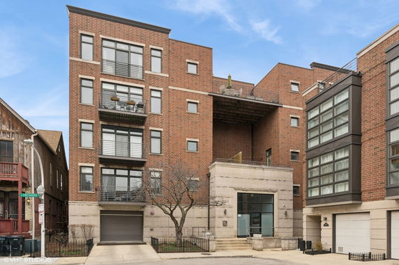 Front view of a multi-story brick apartment building with balconies and large windows.