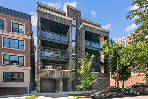 Front view of a modern multi-story building with brick facade and balconies.