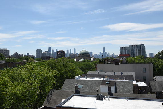 Panoramic view of a city skyline with various buildings and a prominent dome structure surrounded by greenery.