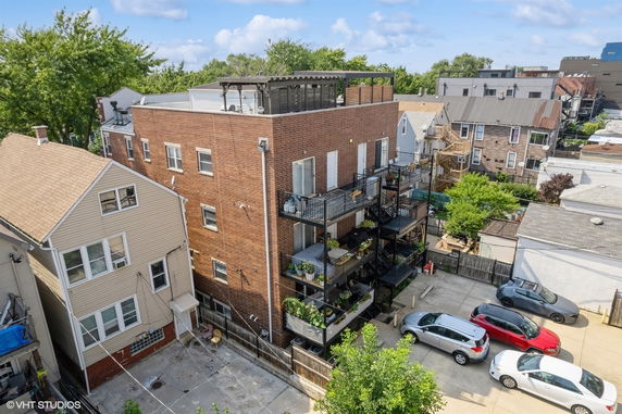 Back view of a multi-story brick building with balconies and a rooftop patio.