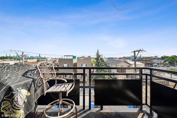 Panoramic view from a balcony overlooking urban buildings and distant city skyline.