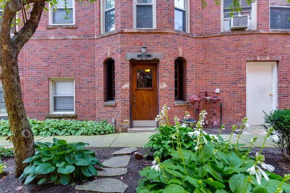 Front view of a two-story brick building with a wooden door and windows.