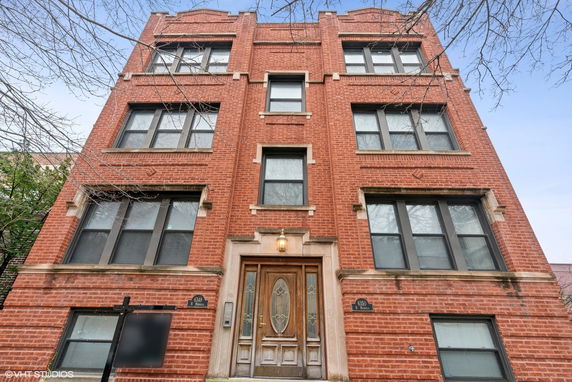 Front view of a multi-story brick building with symmetrical windows and a central entrance.