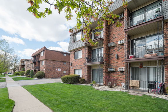 Front view of a multi-story apartment building with balconies and air conditioning units.