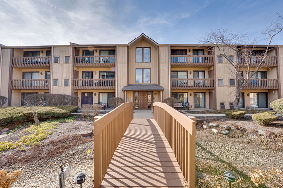 Front view of a multi-story building with balconies and a wooden walkway.