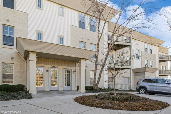 Front view of a multi-story residential building with balconies and an entrance area.