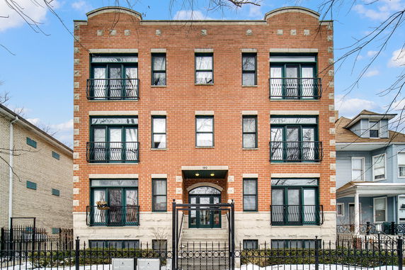 Front view of a three-story brick apartment building with decorative balconies.