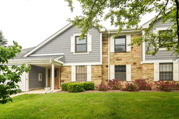 Front view of a two-story house with gray siding and stone accents.