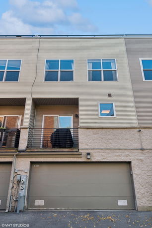 Front view of a multi-story residential building with a garage and balconies.