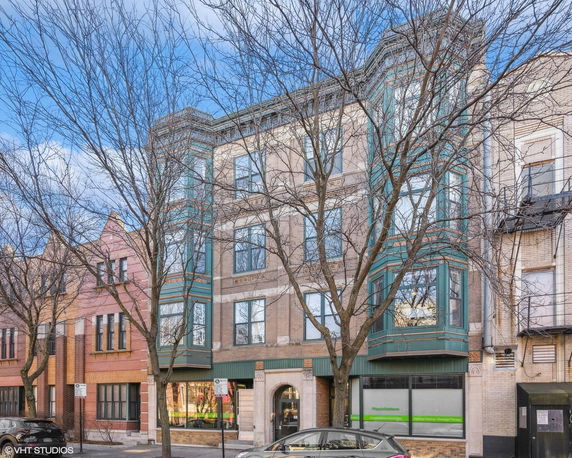 Front view of a multi-story urban building with decorative green framing details.