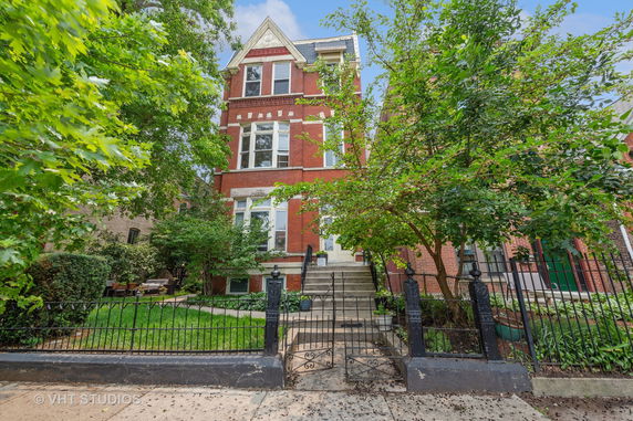 Front view of a multi-story brick house with steps leading to the entrance.