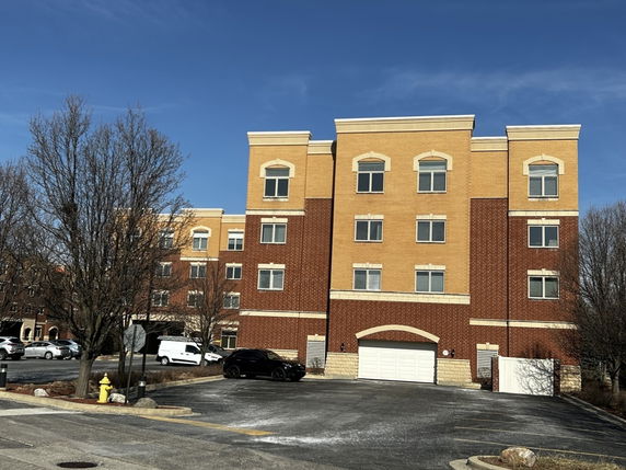 Front view of a multi-story building with a brick facade and parking area.