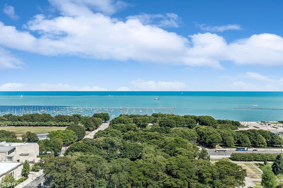 Wide angle view of a coastline with many boats docked in the harbor and a clear blue sky.