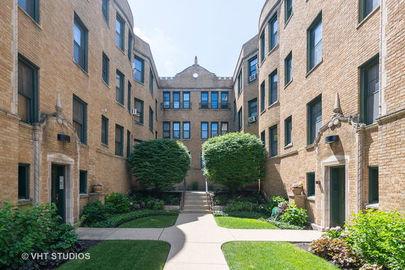 Front view of a multi-story apartment building with brick facade and landscaped entrance.