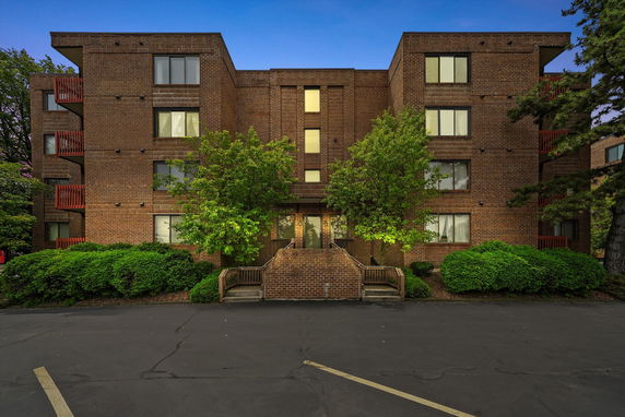Front view of a multi-story brick apartment building with large windows.