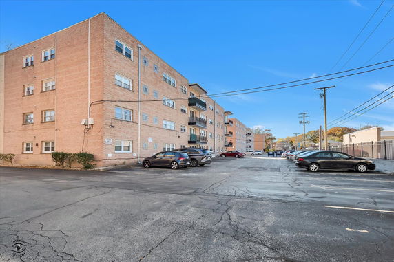Front view of a multi-story apartment building with parking area.
