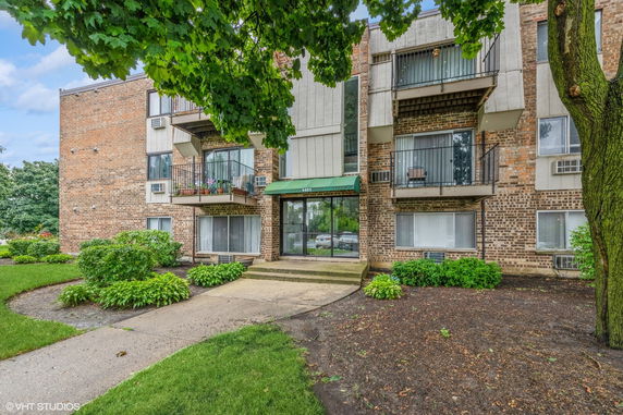 Front view of a multi-story brick apartment building with balconies.