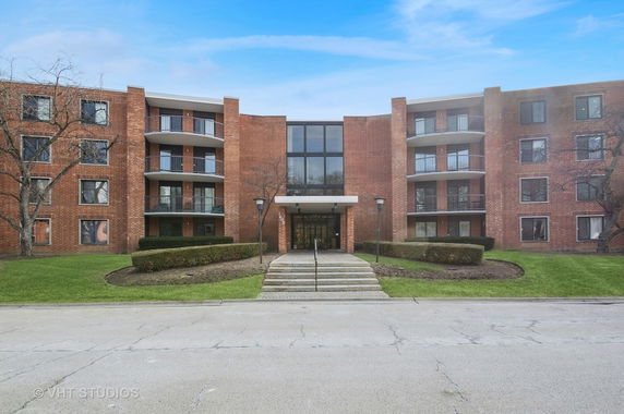 Front view of a multi-story brick apartment building with balconies.