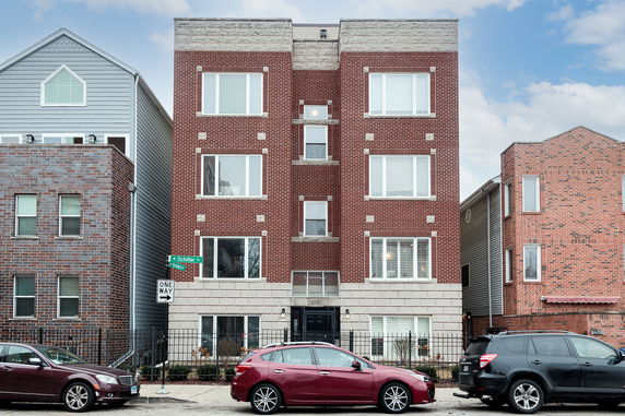 Front view of a multi-story brick apartment building with large windows.