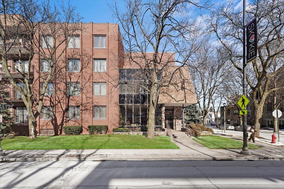 Front view of a multi-story brick building with large glass windows.