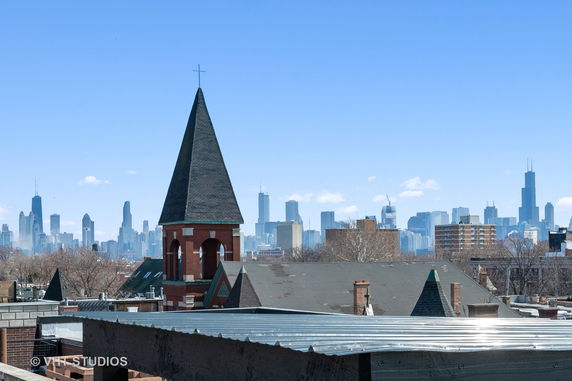 Panoramic view showing a church steeple and city skyline in the background.