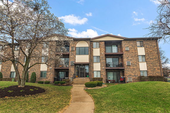 Front view of a multi-story brick apartment building with balconies.