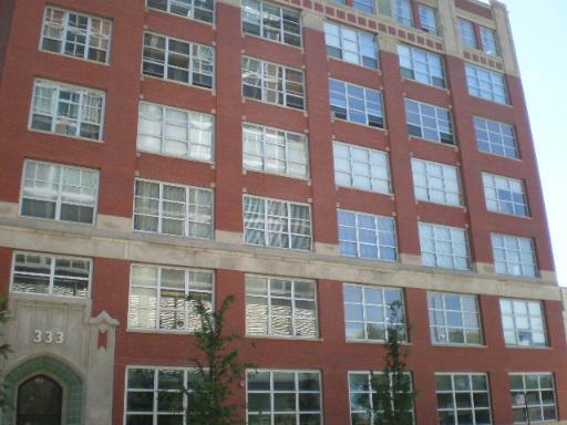 Front view of a multi-story brick building with large windows.