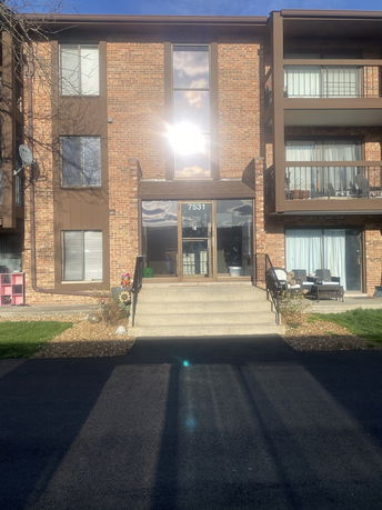 Front view of a multi-story brick building with balconies and a central entrance.
