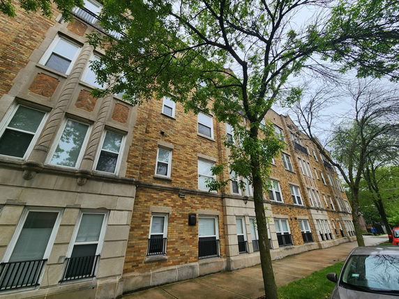 Front view of a multi-story brick apartment building with several windows and decorative elements.
