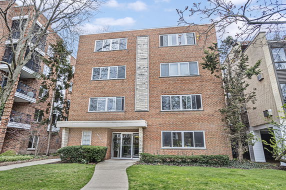 Front view of a four-story brick apartment building with multiple windows.