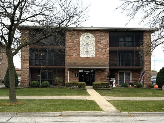 Front view of a three-story brick building with decorative stonework.