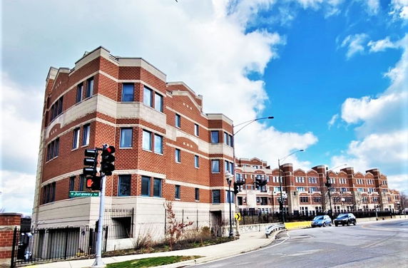 Front view of a multi-story brick residential building on a street corner.