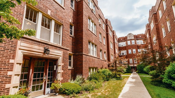 Front view of a multi-story brick apartment building with multiple windows.