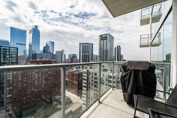 Panoramic cityscape view from a balcony with high-rise buildings.