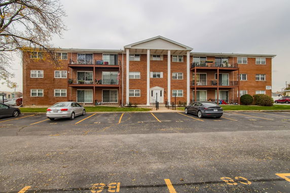 Front view of a three-story apartment building with a brick facade and balconies.