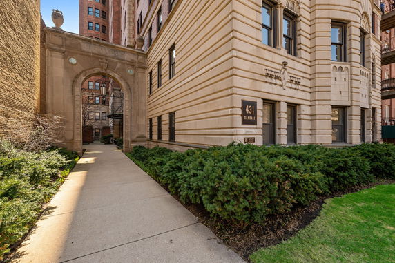 Front view of a multi-story brick building with an arched entry pathway.