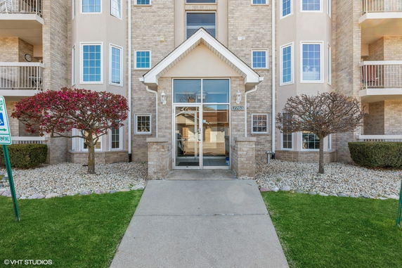 Front view of a multi-story residential building with a glass entrance and brick exterior.
