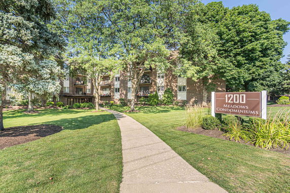 Front view of a condominium building with balconies and surrounding trees.
