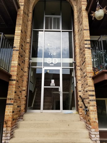 Front view of a building entrance with brick facade and glass door.