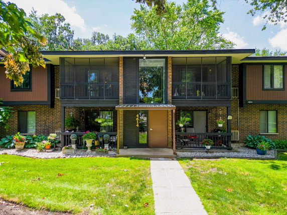 Front view of a two-story apartment building with a brick exterior and screened balconies.