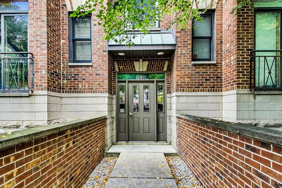 Front view of a brick building entrance with a central door and windows.