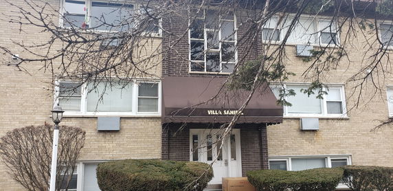 Front view of a multi-story building with a brown entrance canopy and windows with blinds.