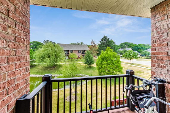 View of surrounding green landscape from a balcony with brick walls.