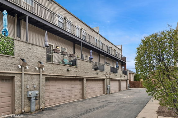 Front view of a multi-story building with balconies and garage doors.