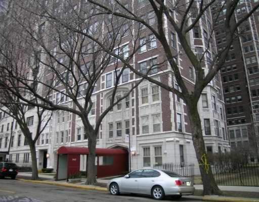 Front view of a multi-story residential building with brick facade and large windows.