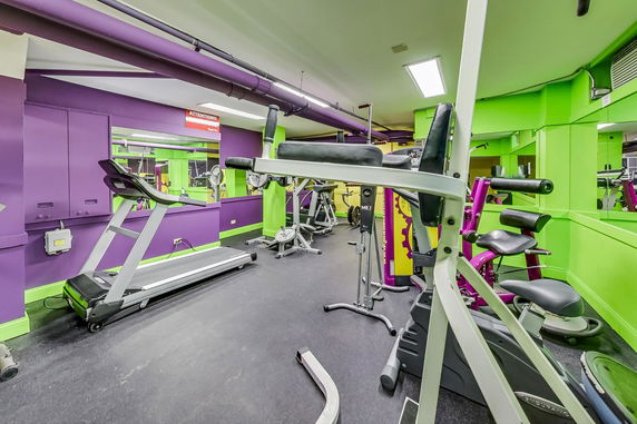 Interior view of a gym area with various exercise equipment and vibrant colored walls.